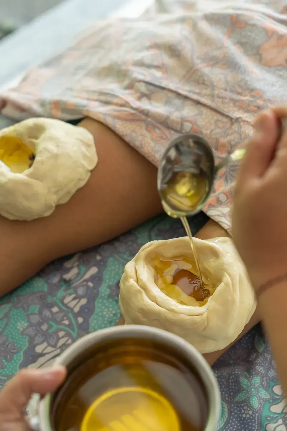 Warm oil being poured into dough boundaries around the knees