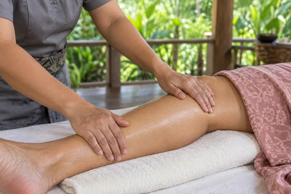 A therapist massaging the calf with both palms